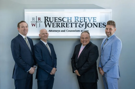 Attorneys of Ruesch Reeve Werrett & Jones standing in front of the firm's sign at their law office in Hurricane, Utah